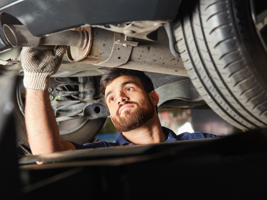 Mechanic inspecting a loud car exhaust system for damage and leaks