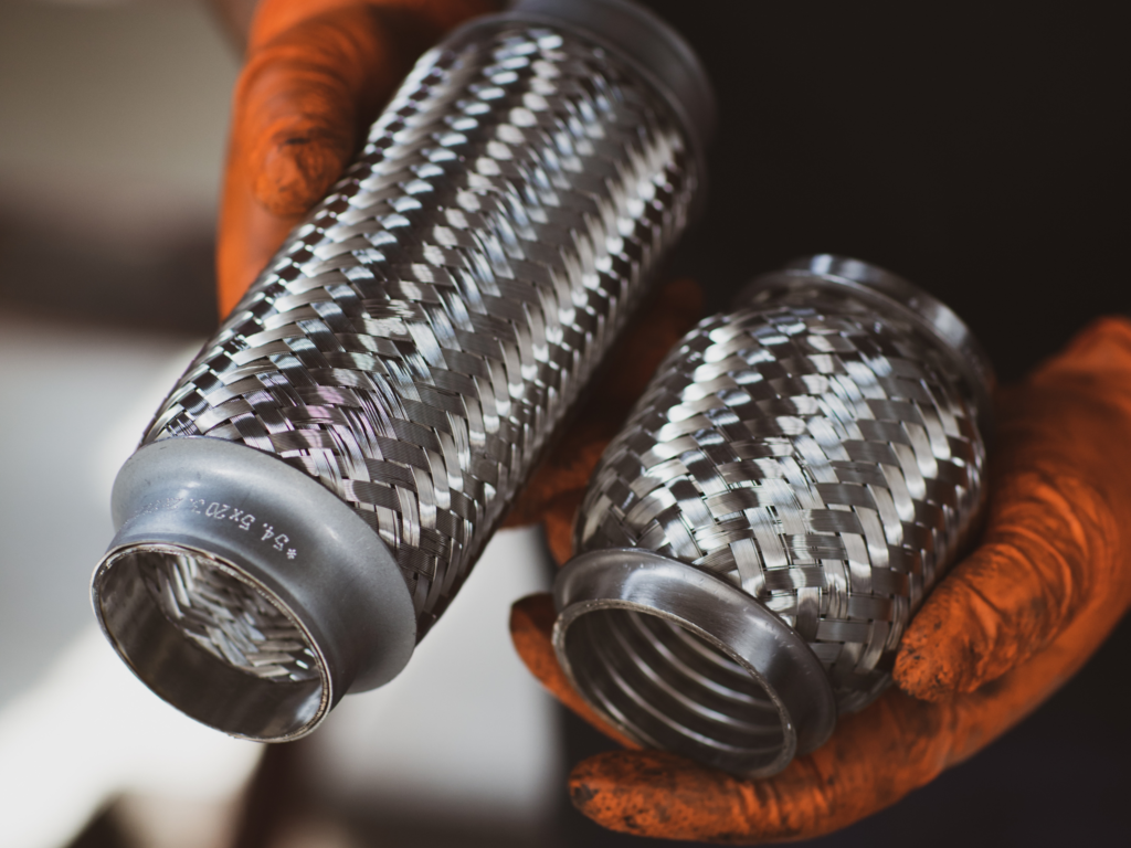 Mechanic replacing a damaged exhaust flexi joint during vehicle repair